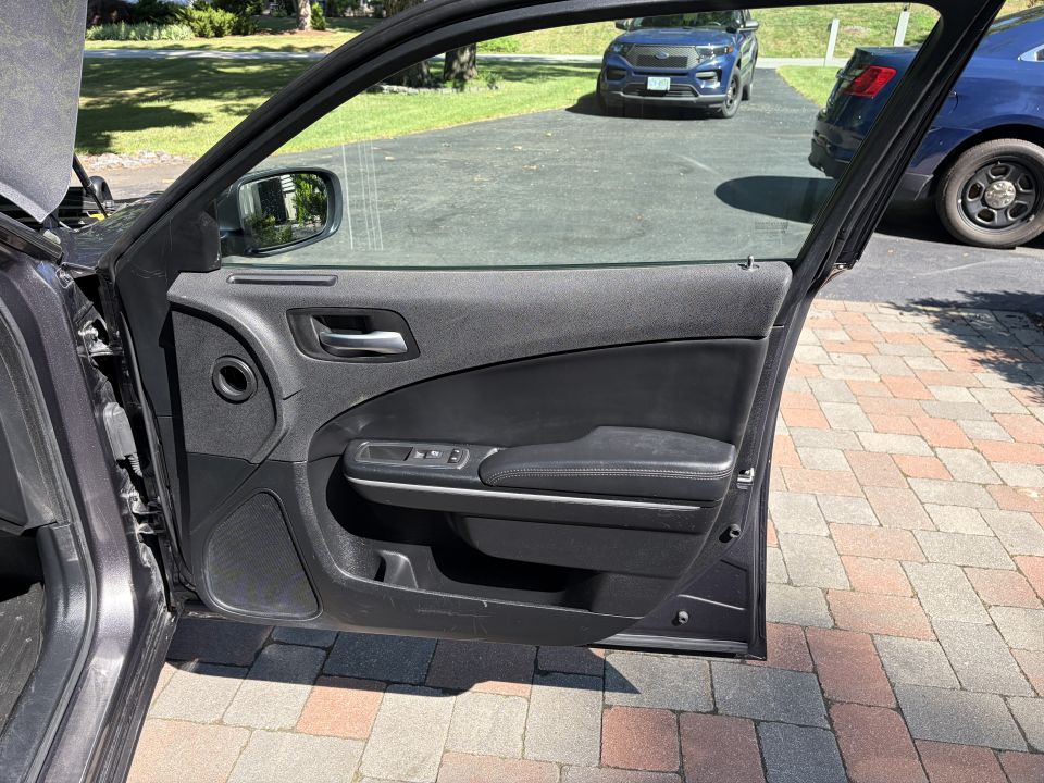 Black inner door panel of open front passenger door on a gray sedan
