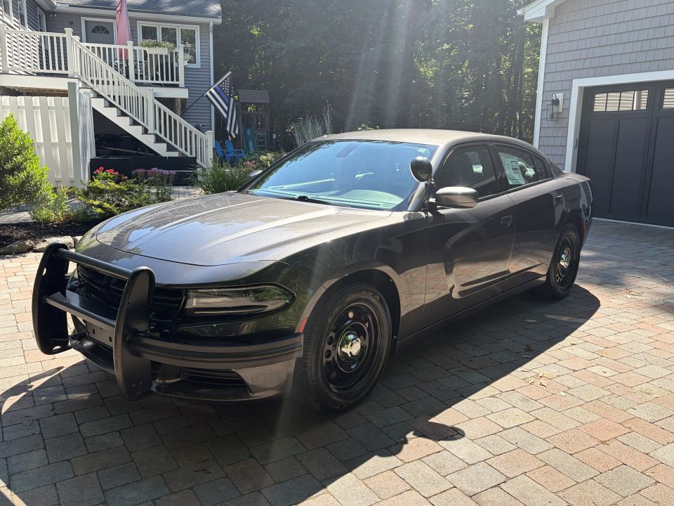 Front 3/4 of dark gray Dodge Charger with black push bumper and steel wheels