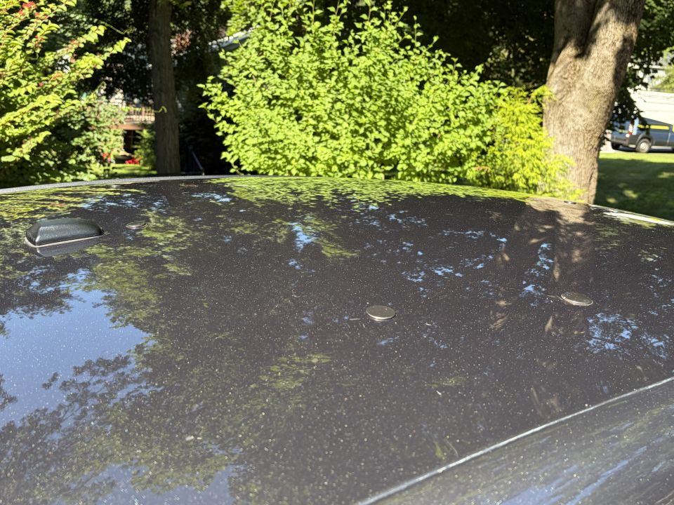 Dark car roof with black antenna pod and chrome plugs covering mounting holes