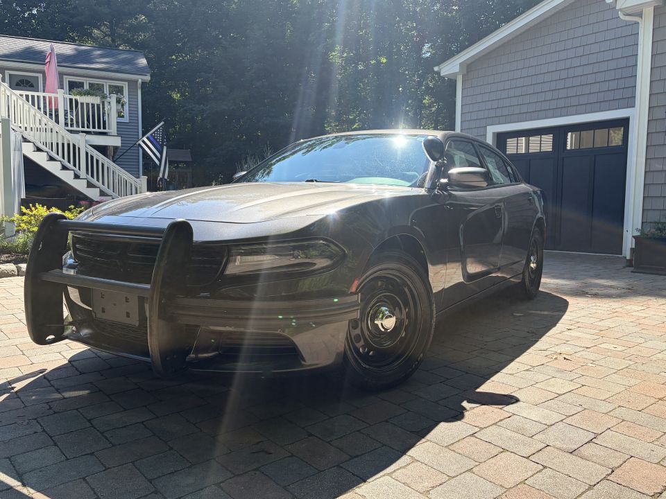 Black Dodge Charger with push bumper and steel wheels parked on paver driveway
