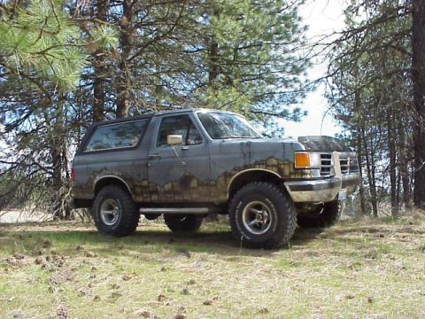 1989 Ford Bronco - This Ford Bronco appears to be from the late 1980s, likely a 1987 model, and is heavily weathered and muddy.