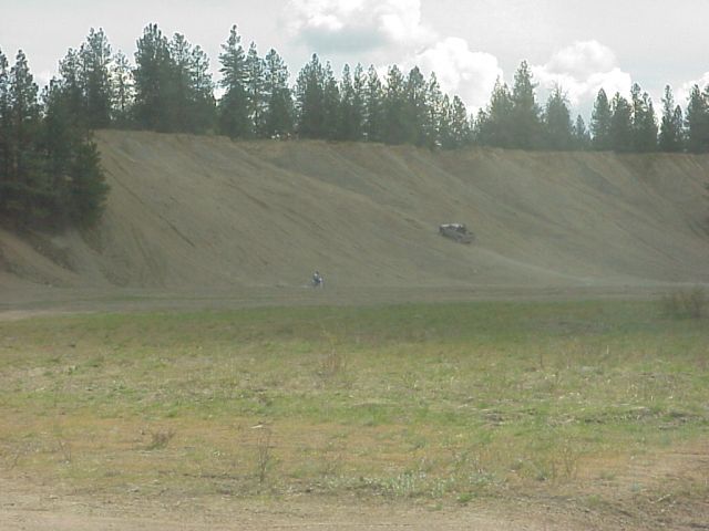 Off-road vehicle on a dirt hill with trees in background