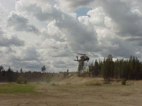 1989 Ford Bronco - A helicopter flies over a dusty landscape under a cloudy sky. The Supermotors.net logo is in the lower right corner.