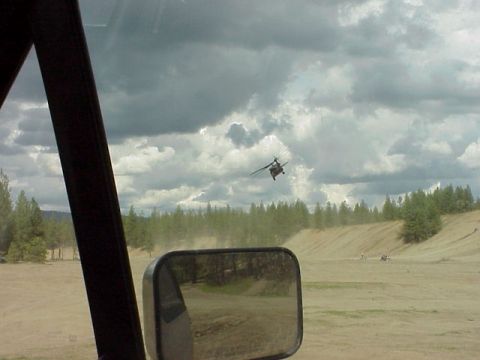 1989 Ford Bronco - A helicopter flies overhead in a dusty, rural landscape, viewed from the interior of another vehicle.