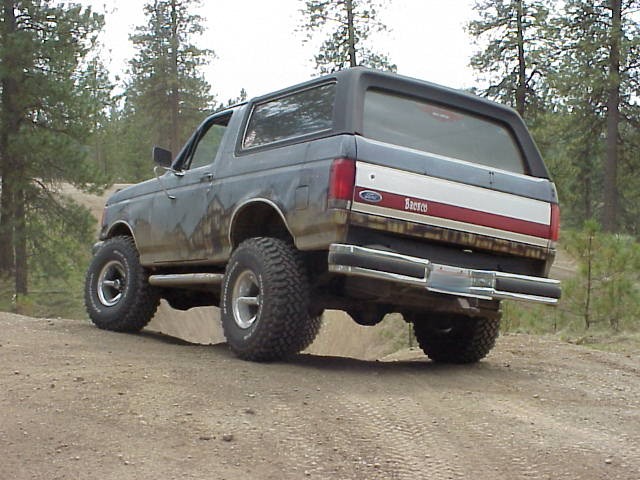 Gray Ford Bronco with red and white stripe on the tailgate, lifted suspension, off-road tires, on a dirt road