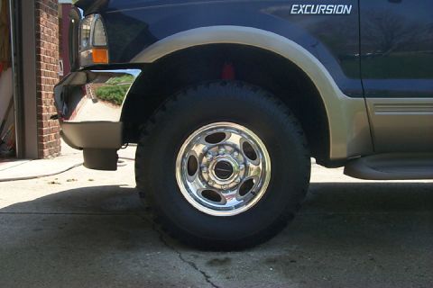 2003 Ford Excursion - The front wheel and fender of a dark blue Ford Excursion with chrome and tan trim details.