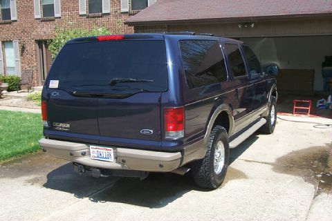 2003 Ford Excursion - Dark blue 2003 Ford Excursion shown from the rear, parked outside a brick house.