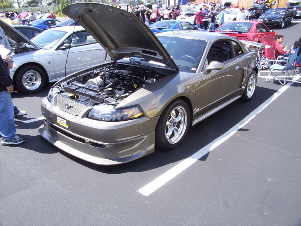 Tan 2002 Ford Mustang GT with hood open, showing engine and custom front bumper