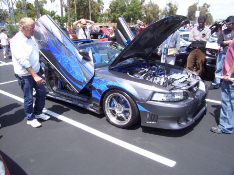 2002 Ford Mustang - A customized 2002 Ford Mustang is displayed with its doors and hood open at an outdoor event.