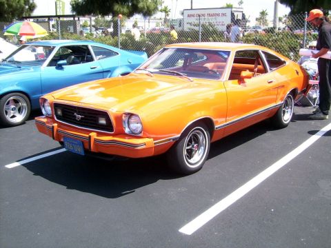 1978 Ford Mustang II - Orange 1978 Ford Mustang II at a car show, with another vehicle visible behind it.