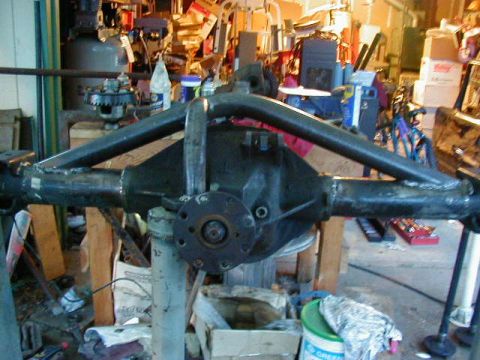 1994 Ford Explorer - A heavily modified rear axle assembly is shown in a workshop setting, with various tools and supplies in the background.