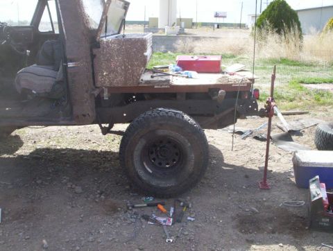 1978 Ford Bronco - A muddy 1978 Ford Bronco, modified with a flatbed, sits with a jack and tools, suggesting ongoing work.
