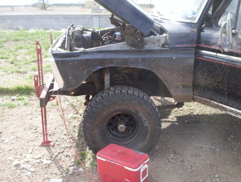 1978 Ford Bronco - Front view of a 1978 Ford Bronco being worked on, with the hood open and a jack supporting the front left.