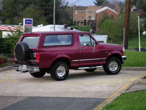 1994 Ford Bronco - Maroon 1994 Ford Bronco parked in a lot with a spare tire on the back.