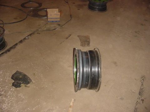 1992 Ford Bronco - A single tire rim is shown on a concrete floor, next to a glove and a box.