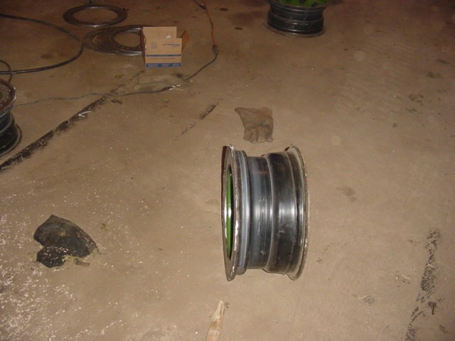 Tire rim on a concrete floor with a work glove and a cardboard box nearby