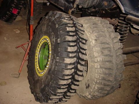 1992 Ford Bronco - Close-up of two large off-road tires, one a custom green rim with a yellow beadlock.