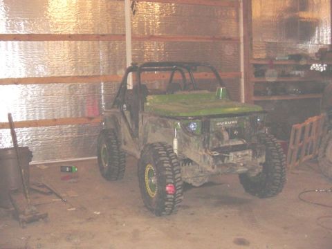 1992 Ford Bronco - Modified Suzuki Samurai with large tires and a roll cage sits in a garage.