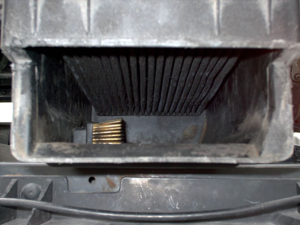 Close-up of pleated air filter element inside a black plastic airbox housing