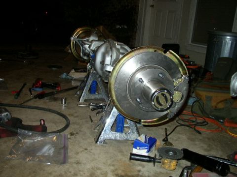 1995 Ford Bronco - Rear axle assembly for a 1995 Ford Bronco, shown on jack stands with brake parts and tools.