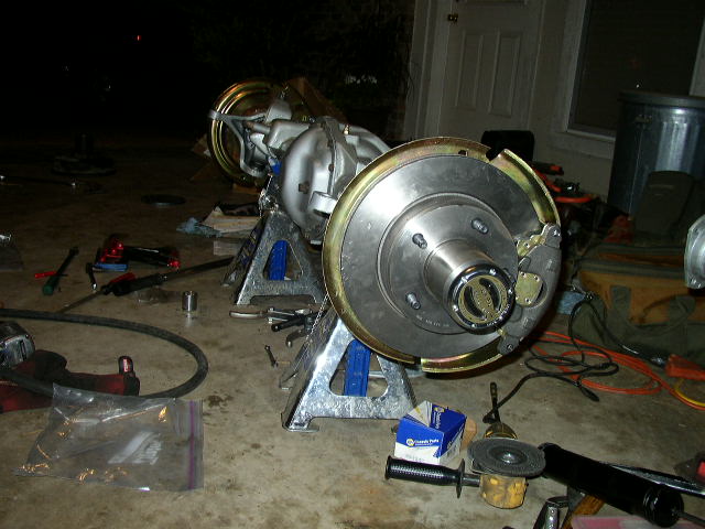 Rear axle assembly on jack stands with drum brake backing plate and hub exposed during seal replacement