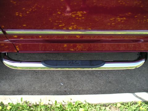 1994 Ford Bronco - Close-up of chrome step bars with black pads on a dark red vehicle.