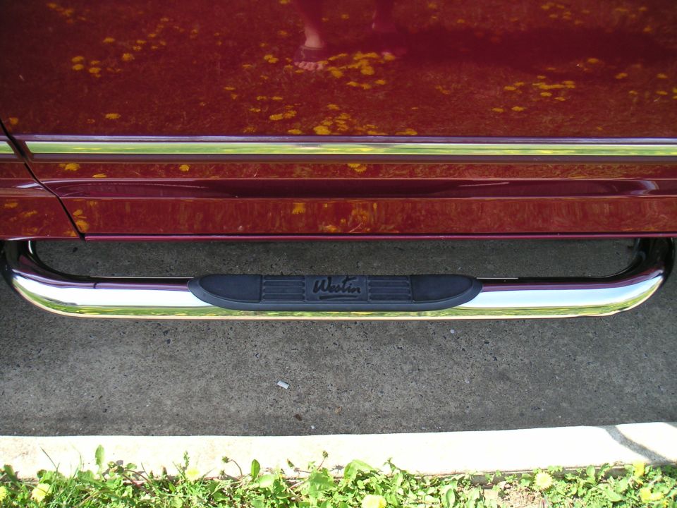 Chrome step bars with black textured pads on a dark red vehicle