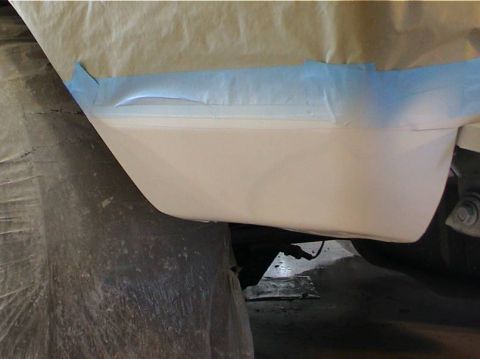 1979 Ford Bronco - A vehicle body panel is masked with blue tape, indicating preparation for a paint job.