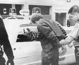 1995 Ford Crown Victoria - A man is apprehended by police officers next to a patrol car outside a funeral home.