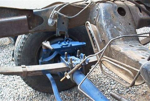 1986 Ford Bronco - Close-up of a blue high steer suspension component attached to a vehicle's leaf spring and frame.