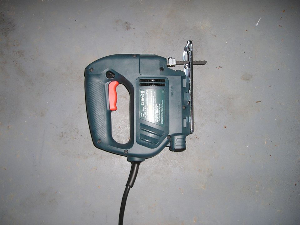 Corded electric jigsaw power tool resting on concrete floor