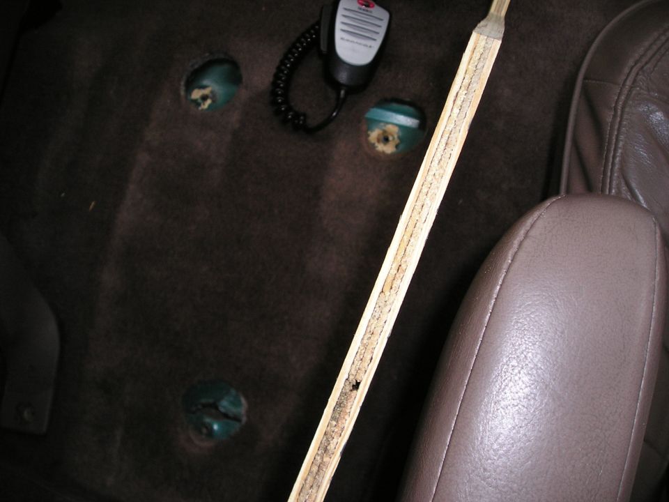 Brown carpet with round cutouts exposing green floor pan seat mounts, CB mic lying nearby