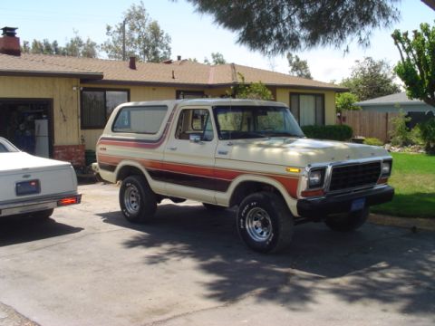 1979 Ford Bronco - A vintage Ford Bronco is parked in a driveway with a house and trees in the background.