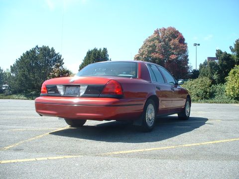 1999 Ford Crown Victoria - Rear view of a red 1999 Ford Crown Victoria parked in a lot on a sunny day.