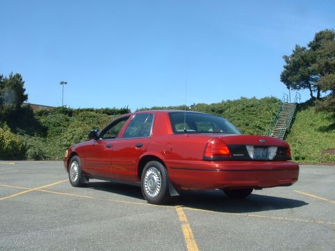 1999 Ford Crown Victoria - Red Ford Crown Victoria parked in a lot under a clear blue sky.