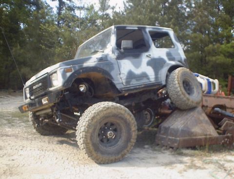 1989 Ford Bronco - This Suzuki Samurai is lifted and has camouflage paint, resting on some debris.