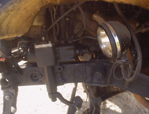 1989 Ford Bronco - Close-up view of a vehicle's undercarriage, showing mechanical components and an auxiliary spotlight.