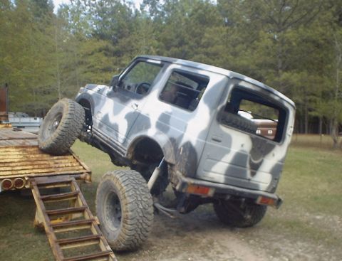 1989 Ford Bronco - A Suzuki Samurai with a camouflage paint scheme is positioned on a trailer ramp.