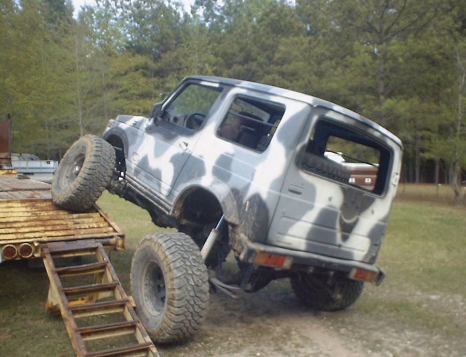 Camouflaged Suzuki Samurai on a trailer ramp