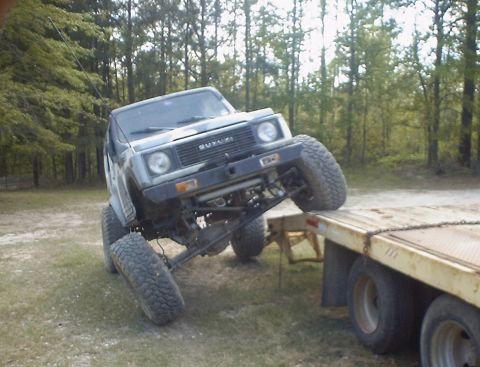 1989 Ford Bronco - Suzuki Samurai with modified suspension is being loaded onto a trailer.