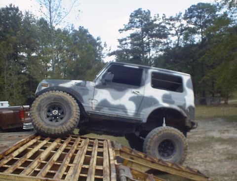 1989 Ford Bronco - An off-road vehicle with a camouflage paint scheme is positioned on a ramp.