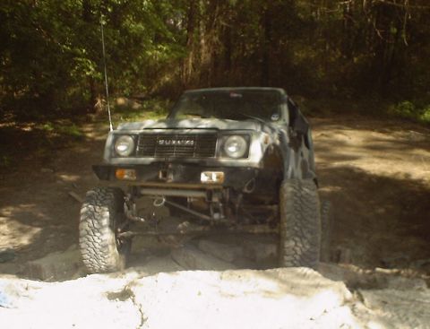 1989 Ford Bronco - A Suzuki Samurai is shown navigating rough terrain with its front wheels angled.