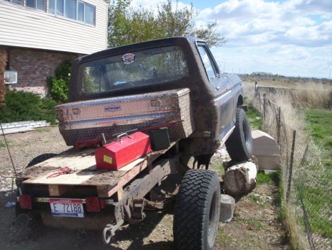 1978 Ford Bronco - A muddy 1978 Ford Bronco is loaded onto a flatbed trailer, with a toolbox and red container visible on the trailer bed.