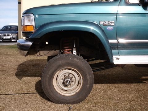 1996 Ford Bronco - Teal 1996 Ford Bronco XLT showing its front wheel, fender, and chrome trim. Another car is visible in the background.