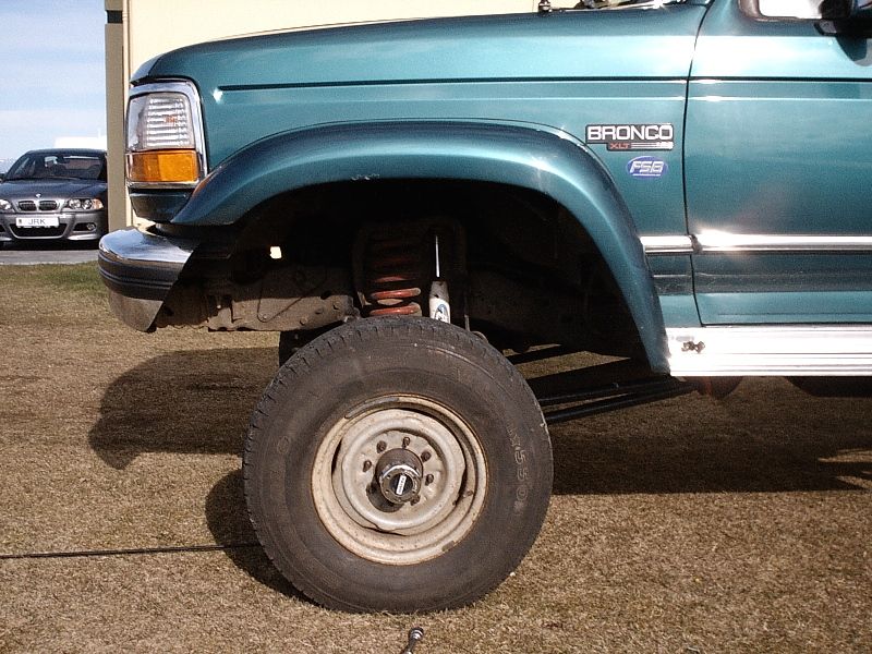 Teal Ford Bronco front fender and lifted suspension with white steel wheel