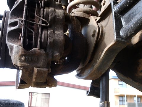 1996 Ford Bronco - Close-up view of a vehicle's brake caliper and suspension system, indicating mechanical components.
