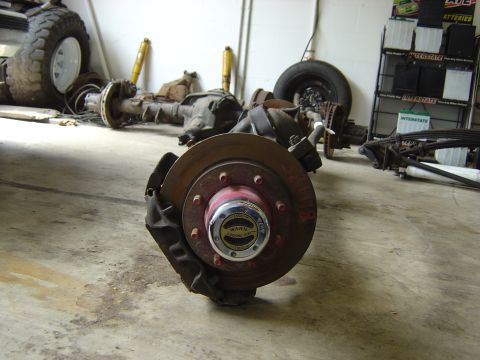 1993 Ford Bronco - Front axle assembly with disc brake and WARN locking hub. Other vehicle parts are in the background.