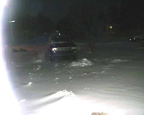1988 Ford C-350 (Centurion Conversions) - A dark pickup truck is parked in a snowy area at night, its front grille and headlights visible.