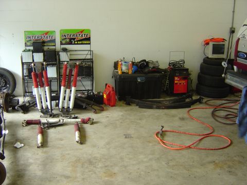 1993 Ford Bronco - Various automotive parts and equipment are organized and stored in a garage setting.