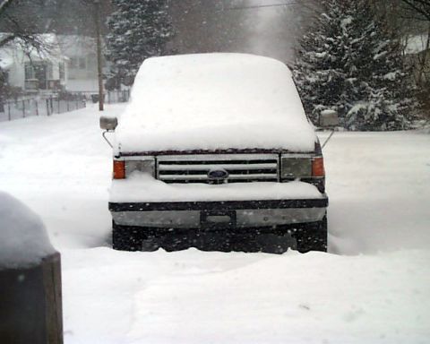 1988 Ford C-350 (Centurion Conversions) - A maroon Ford truck is partially buried in snow, showing its front grille and headlights.